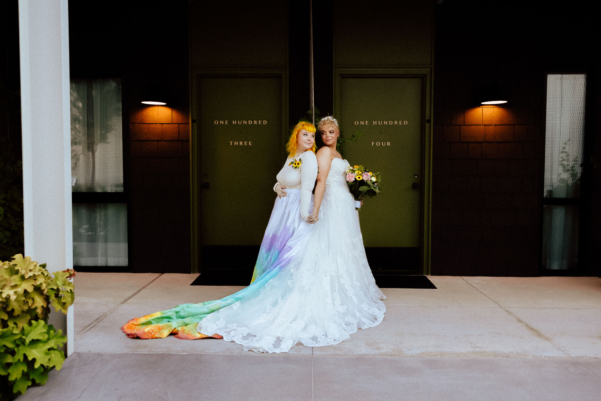 Two brides celebrating in elegant designer bridal gowns from a bridal boutique that welcomes all couples to shop bridal for their wedding day.