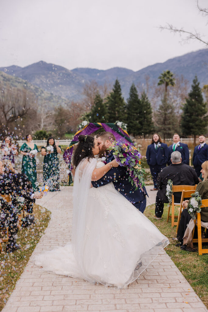 Bride and groom kissing during outdoor ceremony in a romantic designer bridal gown from a bridal boutique, inspiring couples to shop bridal for timeless designer bridal gowns.