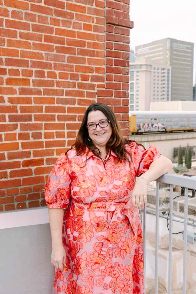 Courtney Hedrick, co-owner of The Formal Niche bridal boutique in Oklahoma City, smiling on a rooftop overlooking downtown OKC.