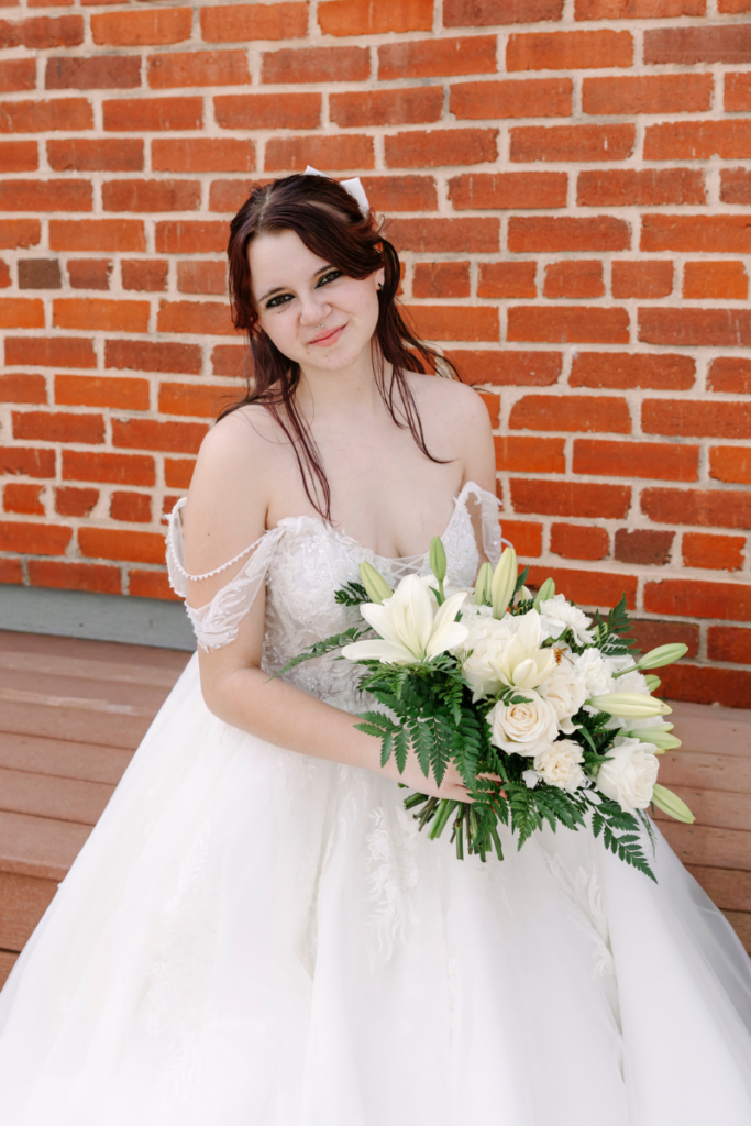 Bride holding a white floral bouquet while wearing a romantic off the rack wedding dress.