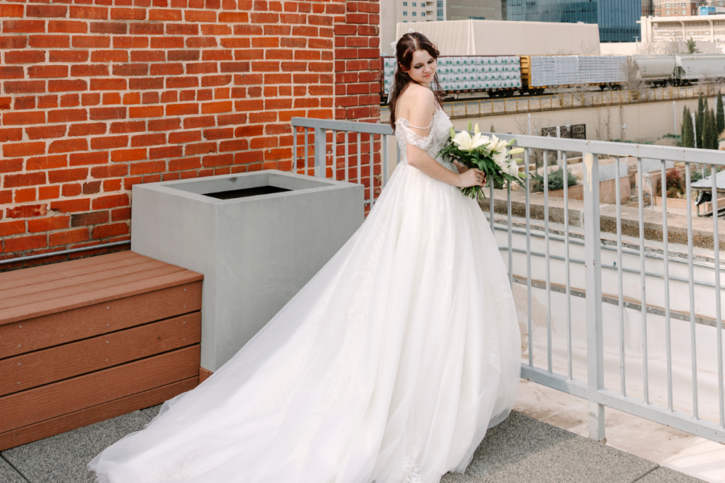 Bride in a lace wedding gown holding a bouquet on a rooftop with bridal tips and wedding dress advice inspiration.