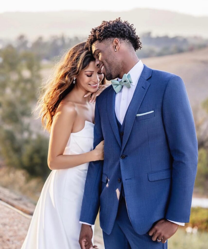 Couple wearing a white formal dress and blue tuxedo with a sage-green bow tie