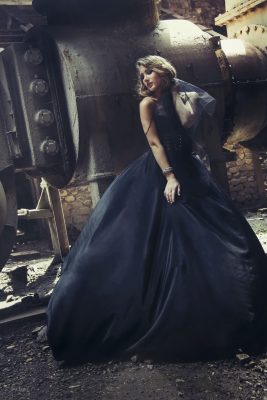 blonde girl in black dress at an old abandoned factory. steampunk